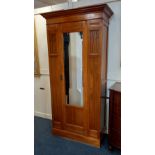 An Arts and Crafts satinwood hall wardrobe with central mirrored door flanked by fretwork panels, on