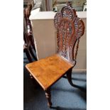 A Victorian carved hall chair, the shaped back with shell surmount above central flower design, on