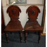 A pair of Victorian hall chairs with shield plaque backs, solid seats on turned baluster legs, (a/