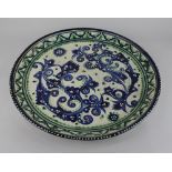 A Middle Eastern glazed pottery charger, decorated in blue, rust and green with foliate design