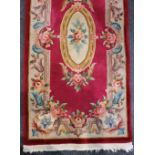 A Chinese runner rug, red ground with floral decoration 77cm by 158cm