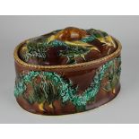 A majolica pottery game pie dish and cover with moulded decoration 18cm (a/f)