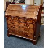 A George III mahogany bureau with fall enclosing fitted interior of small drawers and pigeon holes
