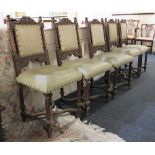 A set of five Flemish style carved oak dining chairs with brass studded panelled backs, scroll