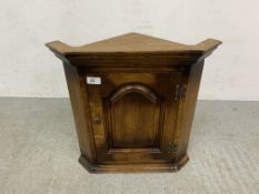 A SMALL OAK REPRODUCTION WALL MOUNTED CORNER CABINET.