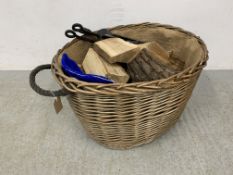 A WICKER LOG BASKET AND A SET OF WROUGHT METAL FIRE TOOLS.