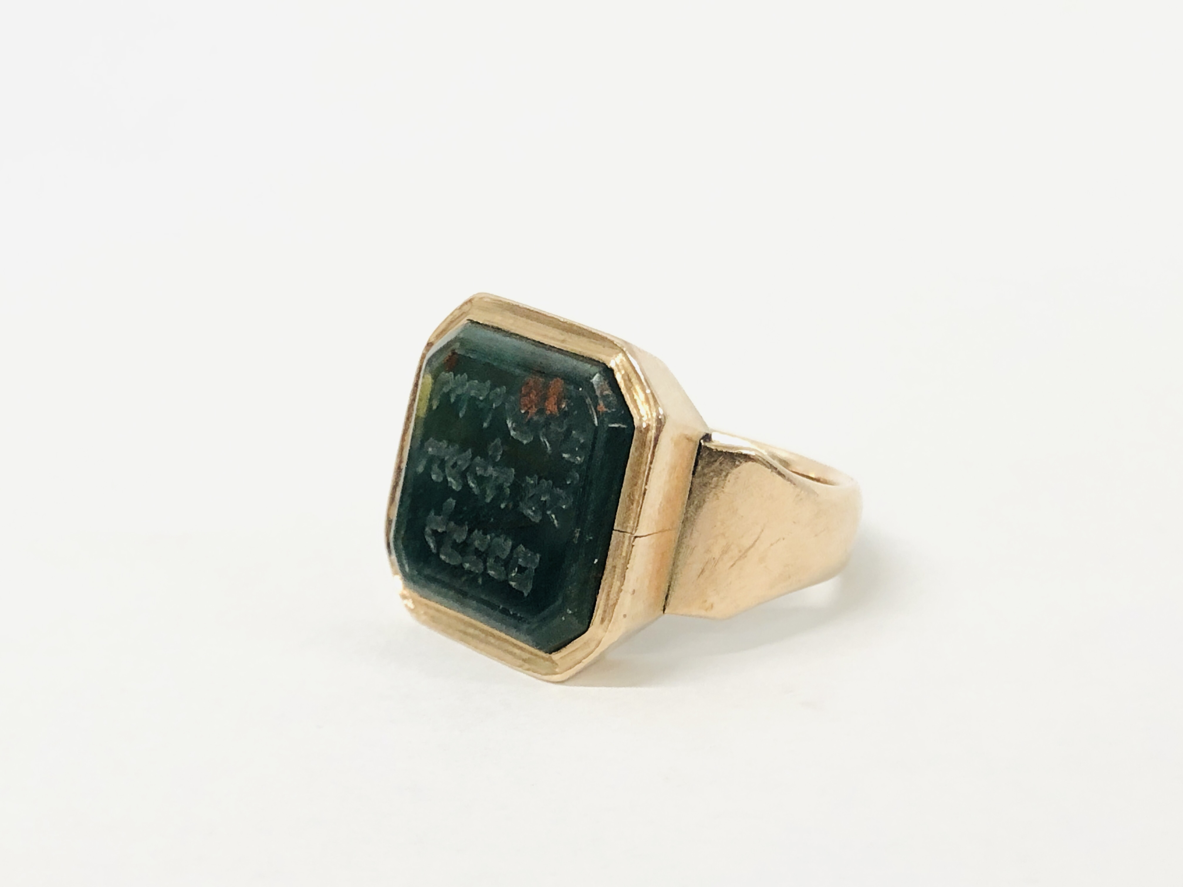 A YELLOW METAL RING & BLOODSTONE SIGNET RING INSCRIBED WITH HEBREW TEXT - SIZE M / N