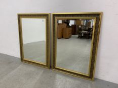 A PAIR OF ORNATE GILT FRAMED BEVELLED WALL MIRRORS EACH W 66CM. H 91CM.