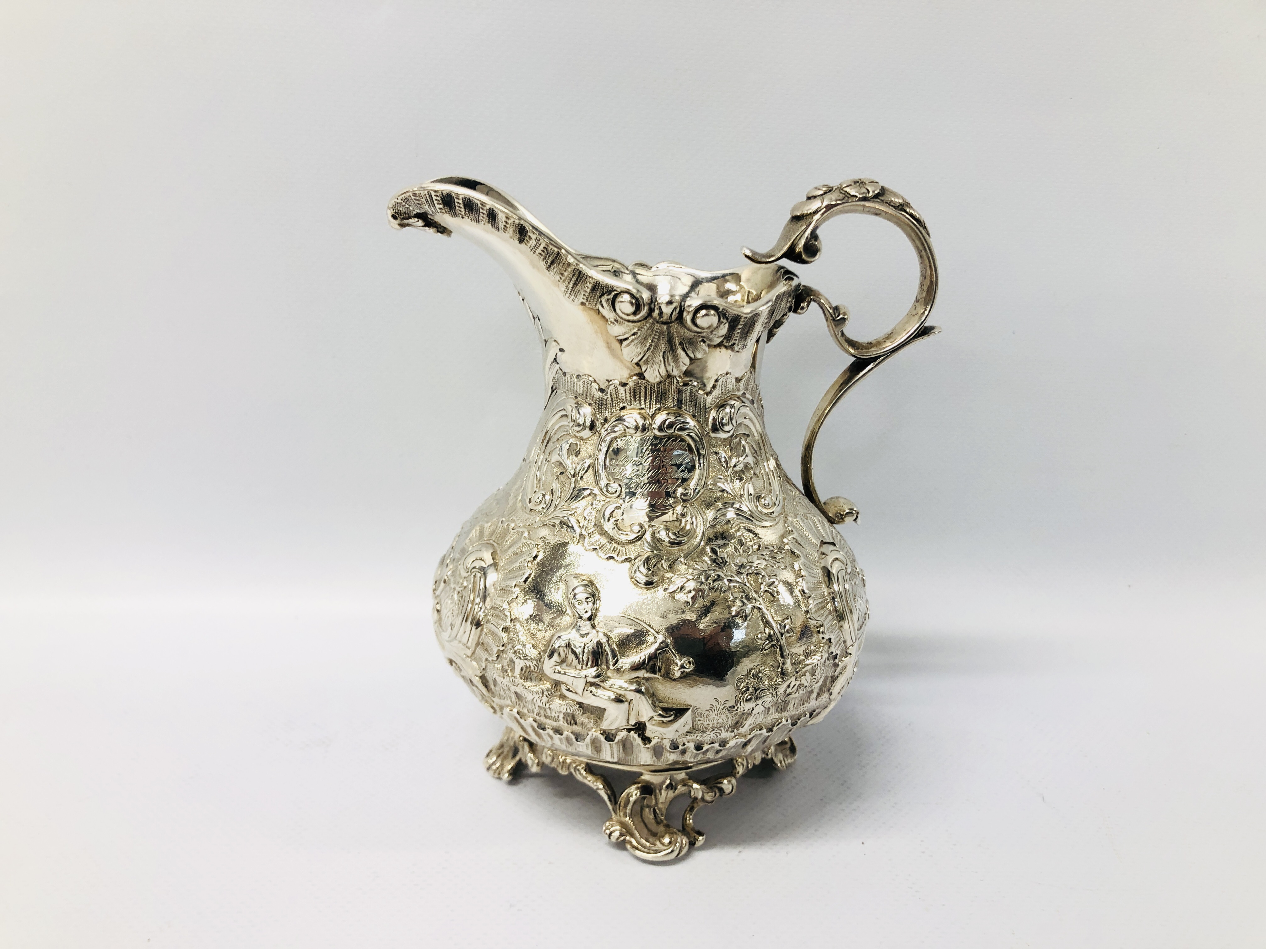 A SILVER MILK JUG OF ROCOCO DESIGN DECORATED WITH CHINOISERIE FIGURES WITH INSCRIPTION MR AND MRS J.