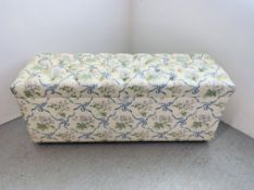 AN UPHOLSTERED OTTOMAN, THE TOP WITH BUTTON BACK DETAIL - W 140CM. D 50CM. H 56CM.