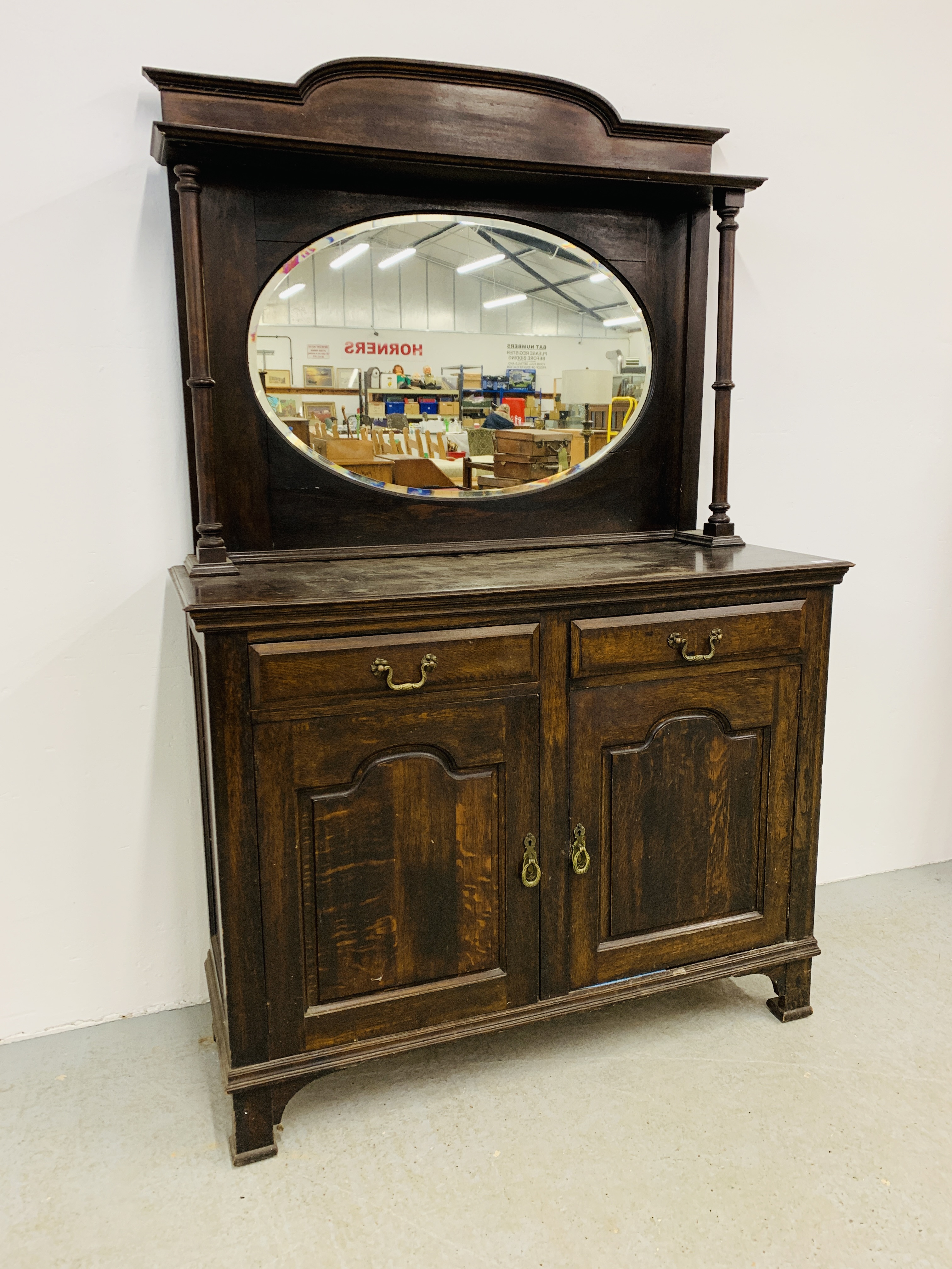 AN OAK 2 DRAWER, 2 DOOR DRESSER WITH MIRROR BACK AND SHELF UPSTAND ON 2 COLUMN SUPPORTS.