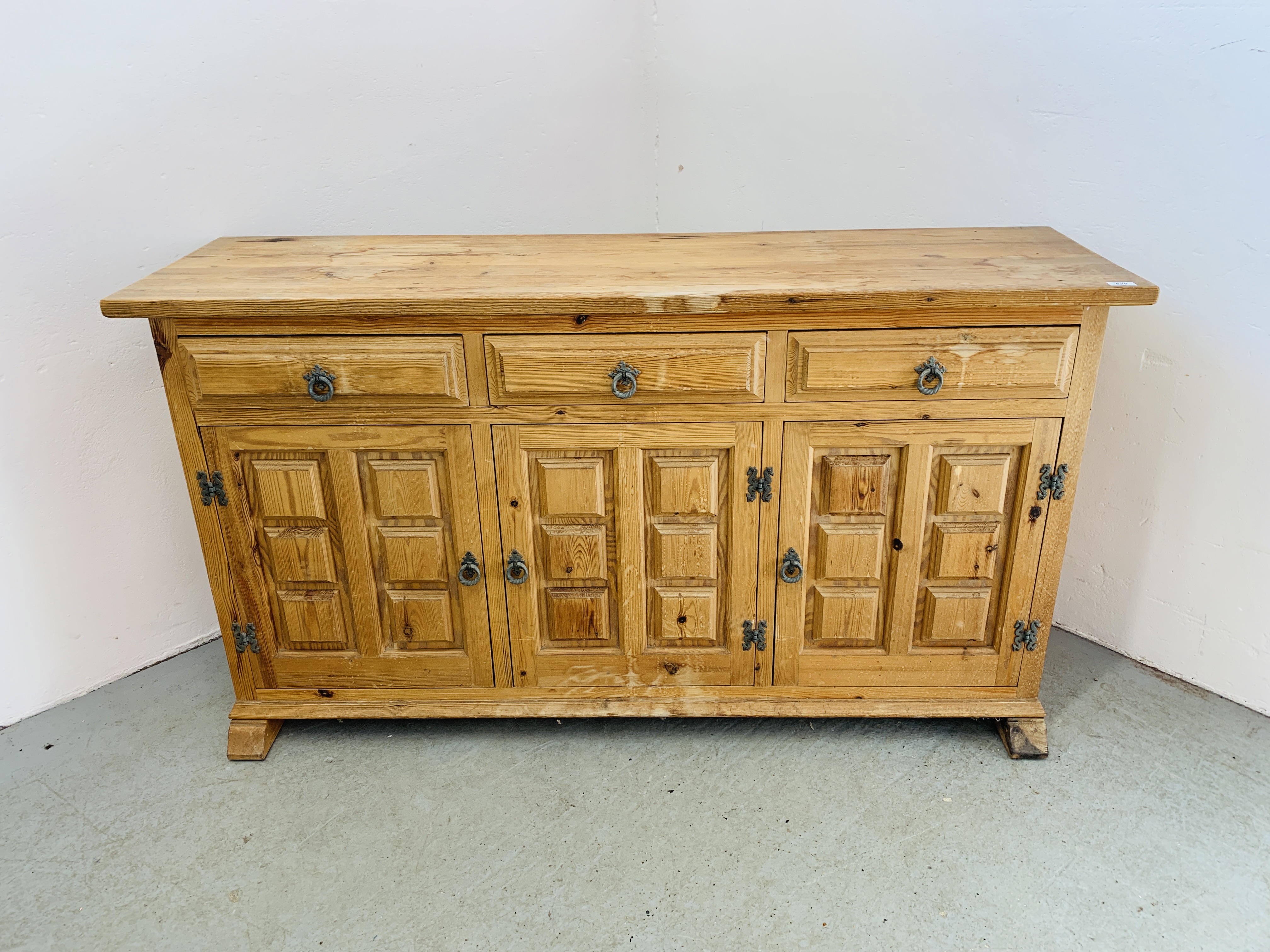 A THREE DRAWER THREE DOOR PINE SIDEBOARD WITH DECORATIVE PANEL DETAIL