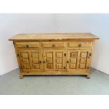 A THREE DRAWER THREE DOOR PINE SIDEBOARD WITH DECORATIVE PANEL DETAIL