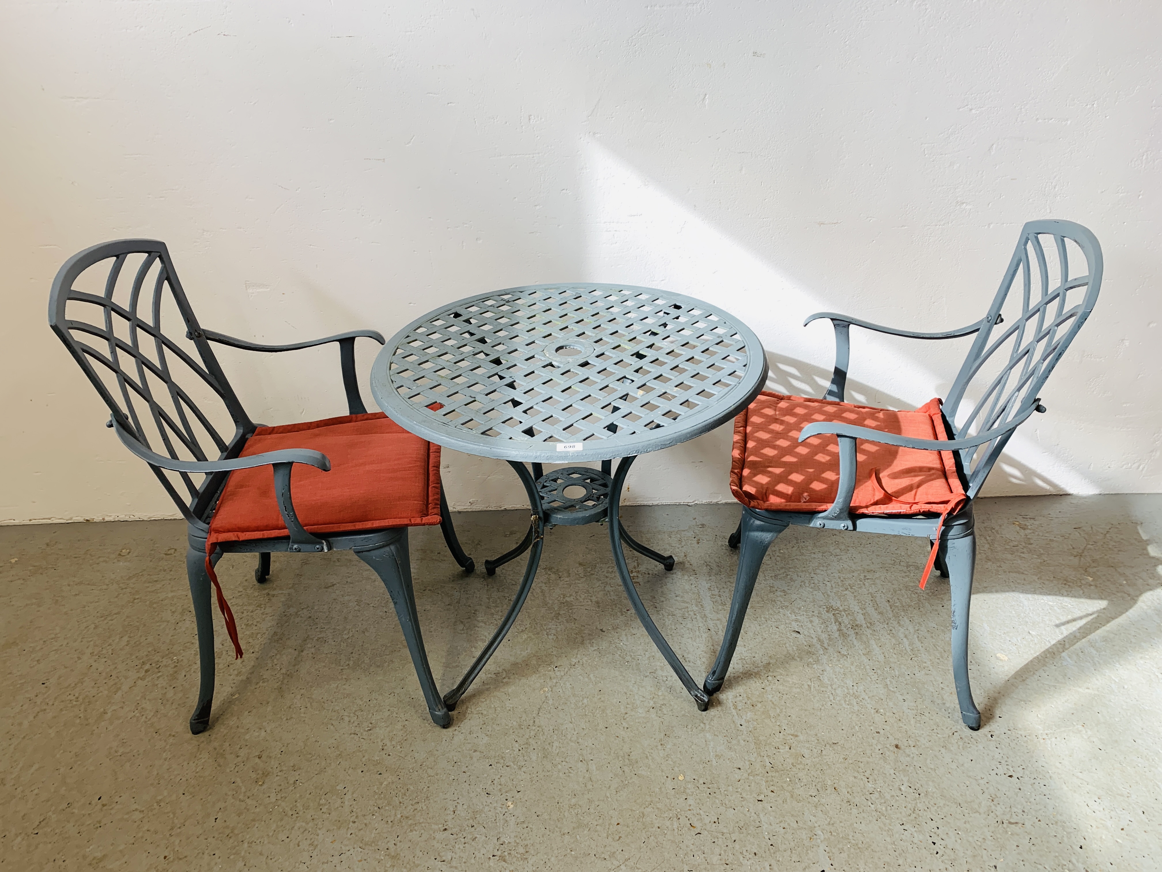 A CAST ALUMINIUM PATIO BISTRO SET COMPRISING CIRCULAR TABLE AND TWO CHAIRS WITH SEAT CUSHIONS