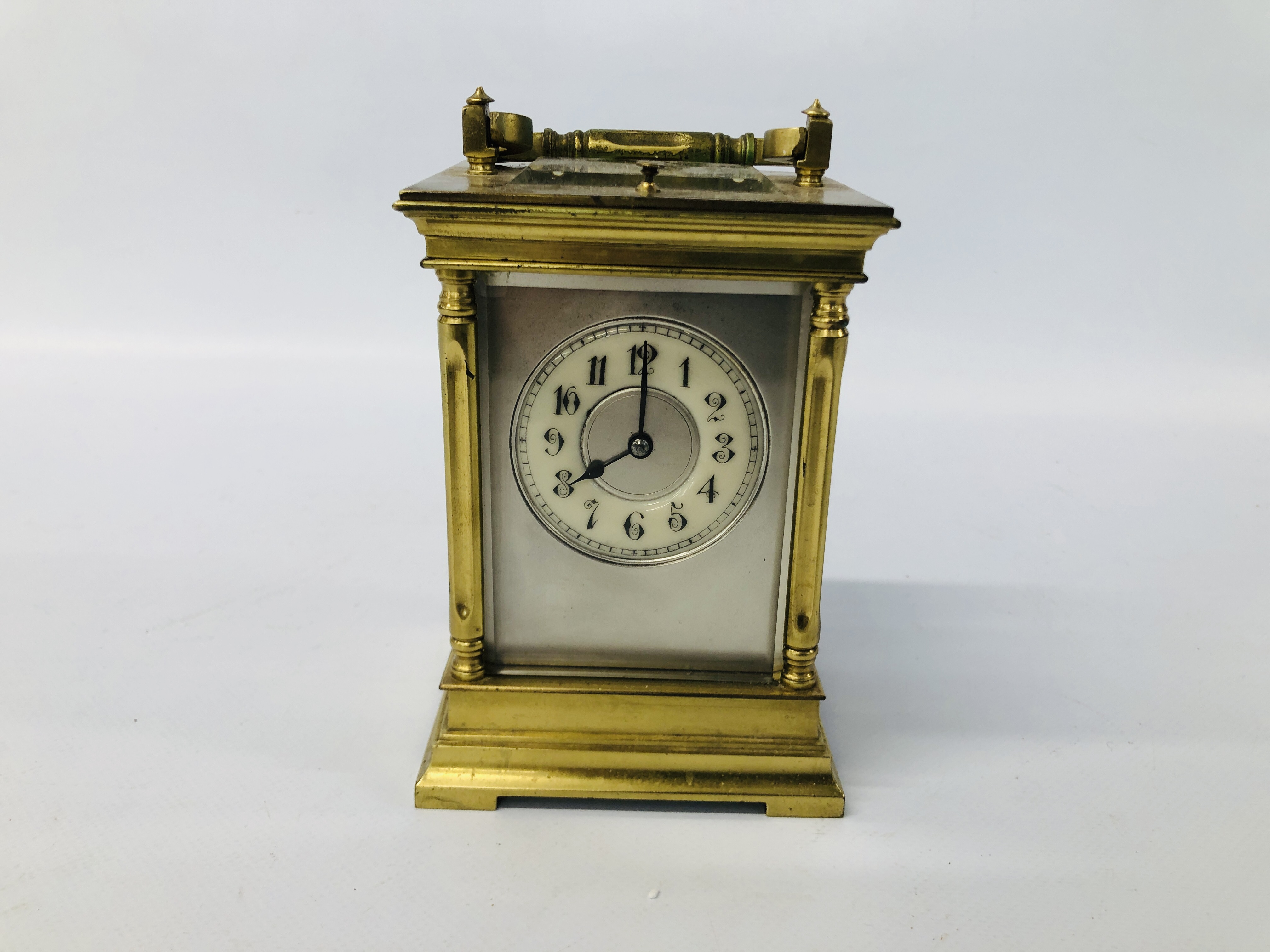 ANTIQUE BRASS CARRIDGE CLOCK WITH ENAMELLED FACE (REQUIRES ATTENTION TO THE REAR GLASS) H 14CM.