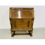 AN OAK 1930'S TWO DRAWER WRITING BUREAU WITH CARVED DETAIL AND BULBOUS FORE LEGS.