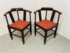 A PAIR OF OAK FRAMED CORNER CHAIRS WITH BARLEY TWIST DETAIL AND RED UPHOLSTERED SEAT