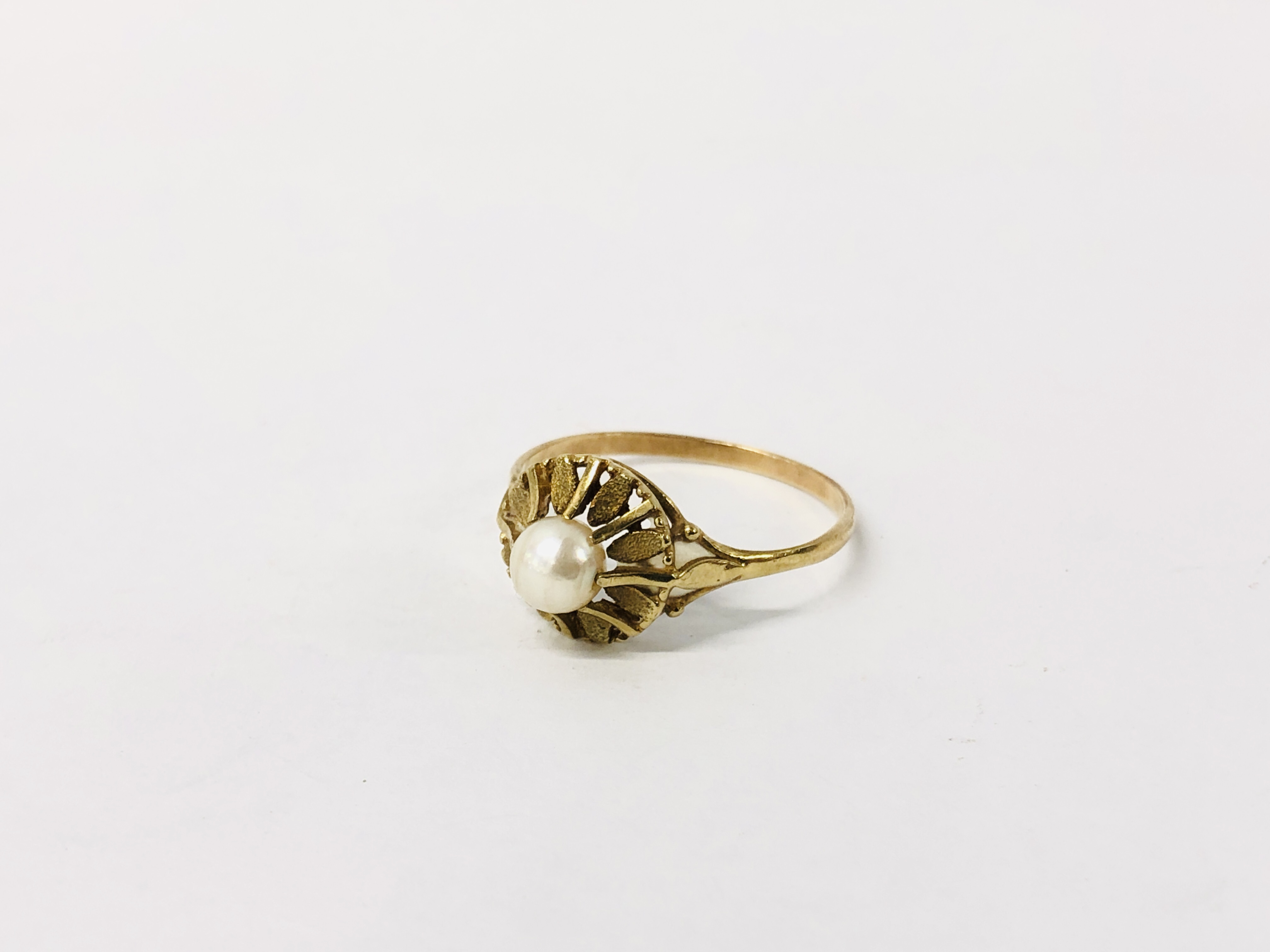 A PEARL RING, A SINGLE CLAW SET STONE, ON AN UNMARKED YELLOW METAL BAND.