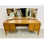 A RETRO TEAK FOUR DRAWER DRESSING TABLE WITH TRIPLE MIRRORS.