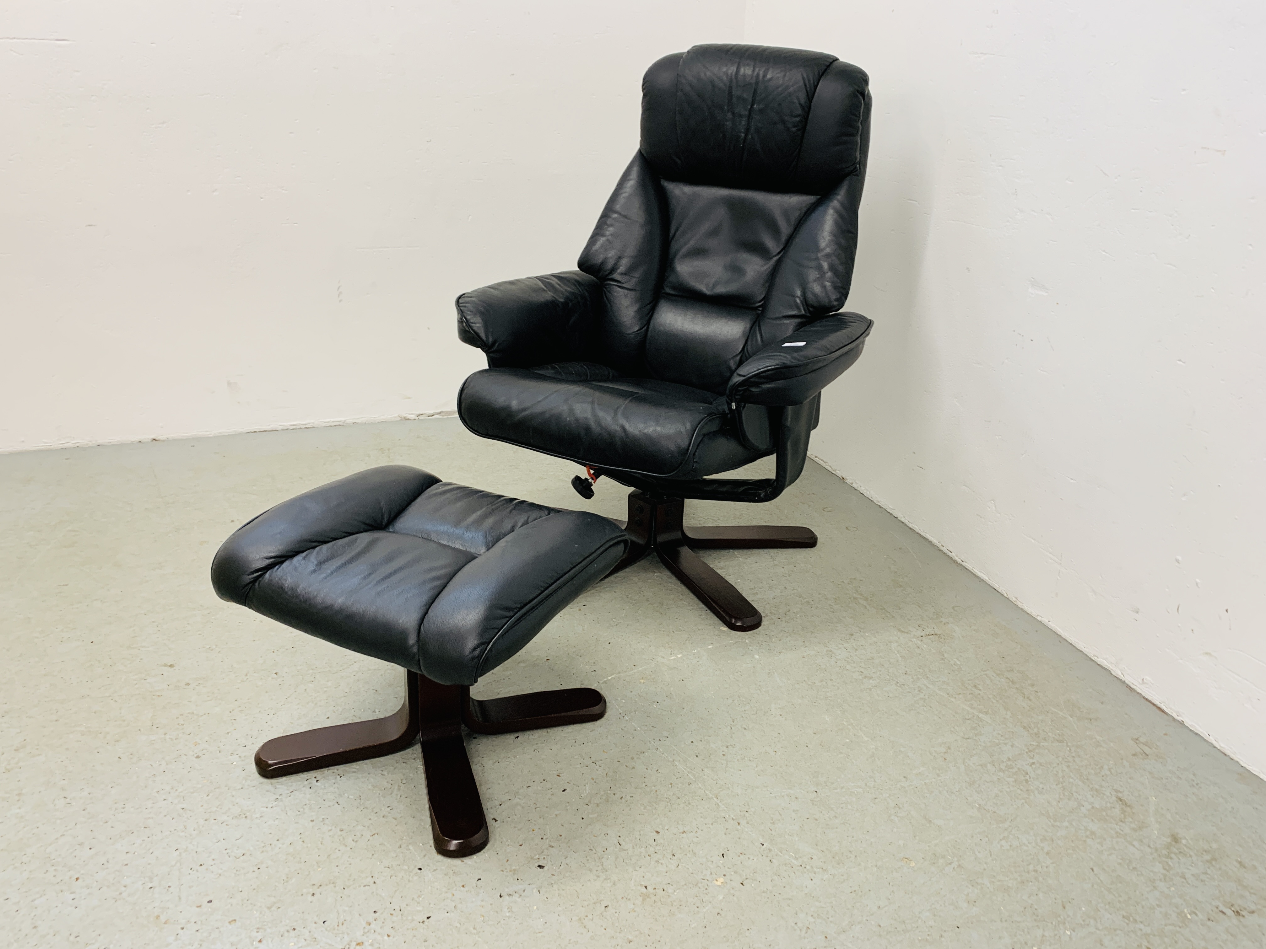 A BLACK LEATHER RELAXER CHAIR AND MATCHING FOOT STOOL.