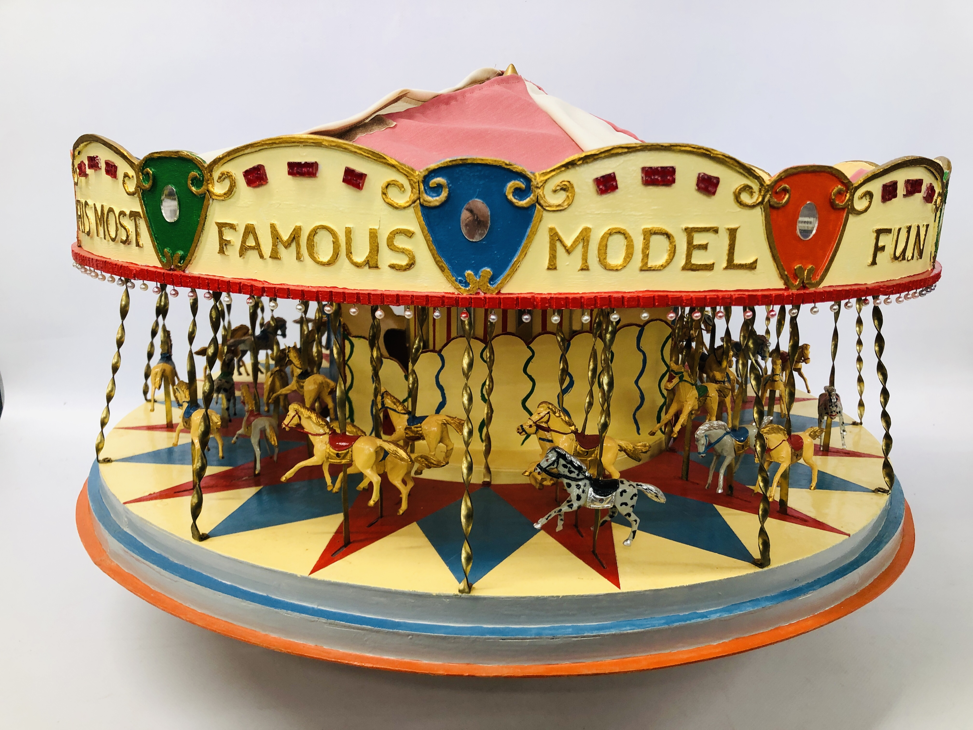 A VINTAGE HANDCRAFTED WOODEN MODEL OF A FAIRGROUND CAROUSEL WITH MOTORISED ACTION AND LIGHTS -