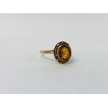 A 9CT GOLD RING SET WITH A SINGLE OVAL AMBER STONE IN A ROPE TWIST FRAME.