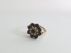 9CT GOLD LADIES RING, FLOWER HEAD DESIGN SET WITH GARNETS AND SEED PEARLS (1 SEED PEARL MISSING).