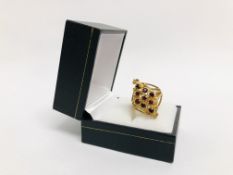 UNUSUAL DESIGNER RING MARKED 9CT GOLD, SET WITH 9 SMALL RUBY COLOURED STONES IN A DIAMOND SETTING.