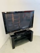 A PANASONIC 42 INCH TELEVISION WITH REMOTE ON BLACK 3 TIER ENTERTAINMENT STAND - SOLD AS SEEN.