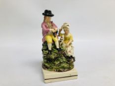 A STAFFORDSHIRE GROUP OF A SEATED BAGPIPER, A LADY AND A DOG, ON A SQUARE BASE (REQUIRES ATTENTION).