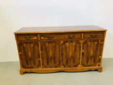 A REPRODUCTION YEW WOOD FINISH THREE DRAWER, FOUR DOOR SIDEBOARD W 110CM, D 35CM, H 194CM.