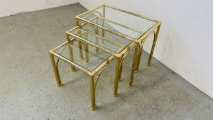 A SET OF THREE DESIGNER BRASSED FRAME GRADUATED OCCASIONAL TABLES WITH GLASS TOPS.