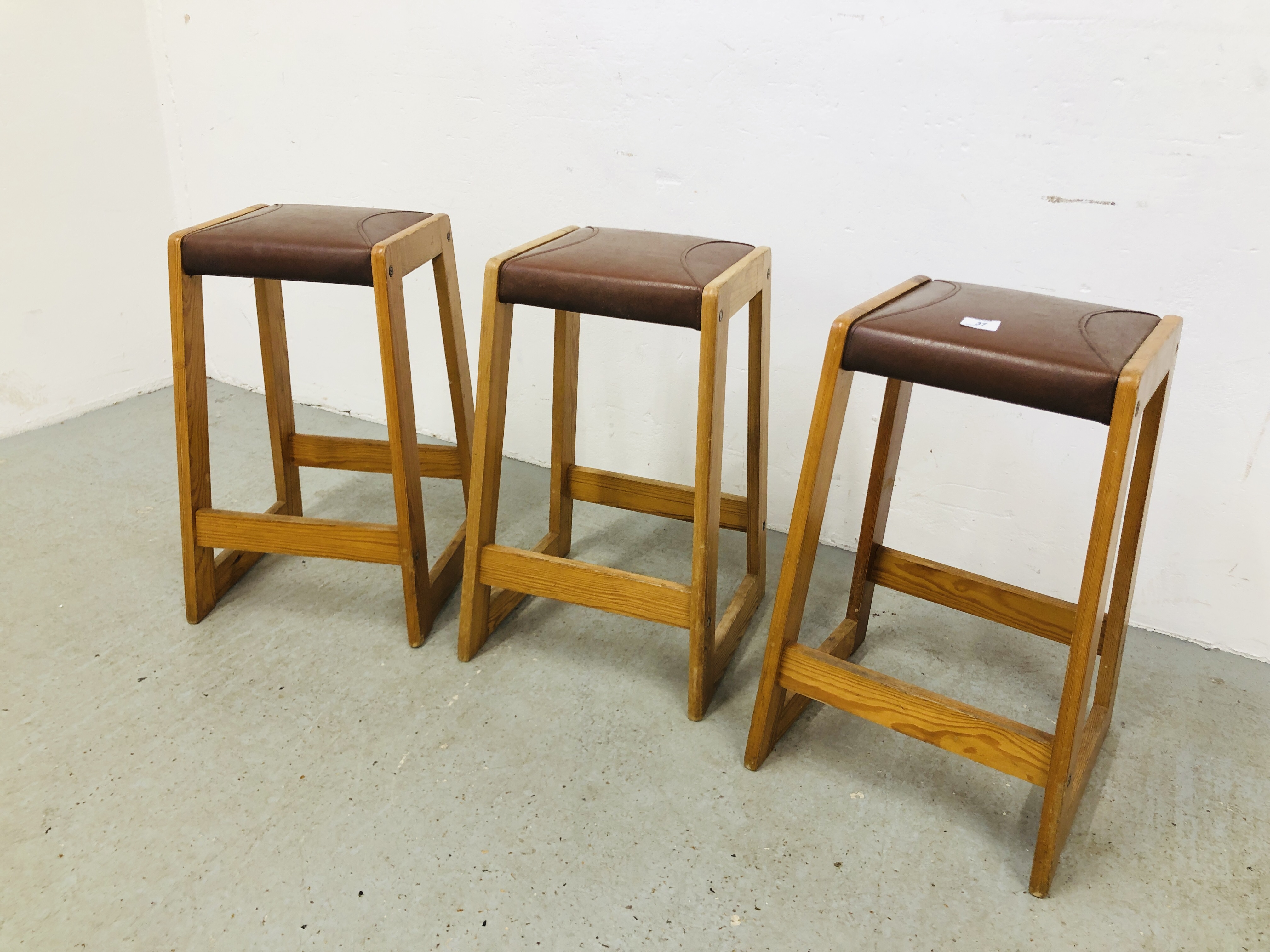 THREE PINE FRAMED BREAKFAST BAR STOOLS WITH BROWN LEATHER PADDED SEAT HEIGHT 62CM.