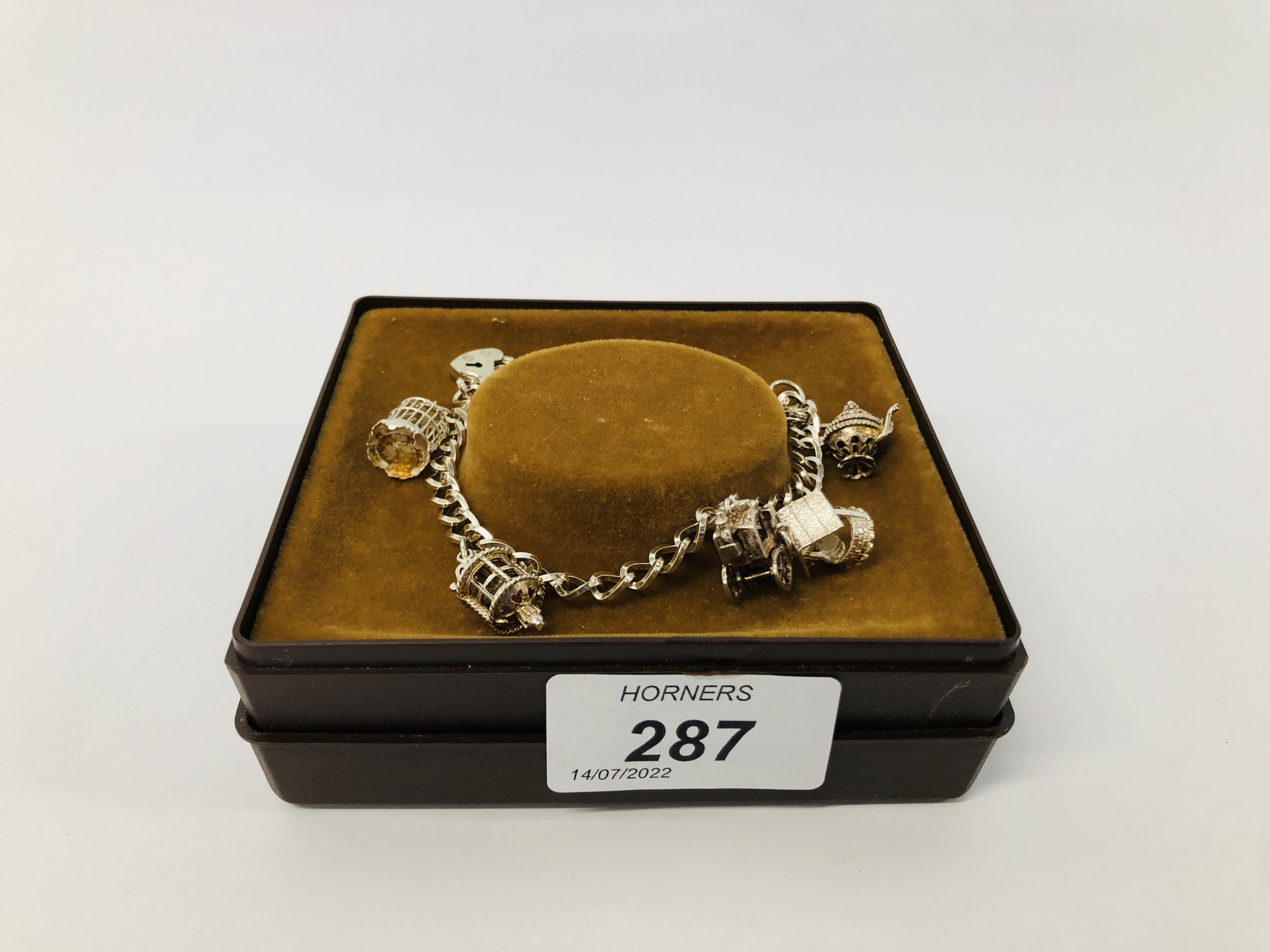 A SILVER CHARM BRACELET WITH FIVE ATTACHED CHARMS TO INCLUDE BIRD CAGE, WISHING WELL, CART ETC. - Image 7 of 8