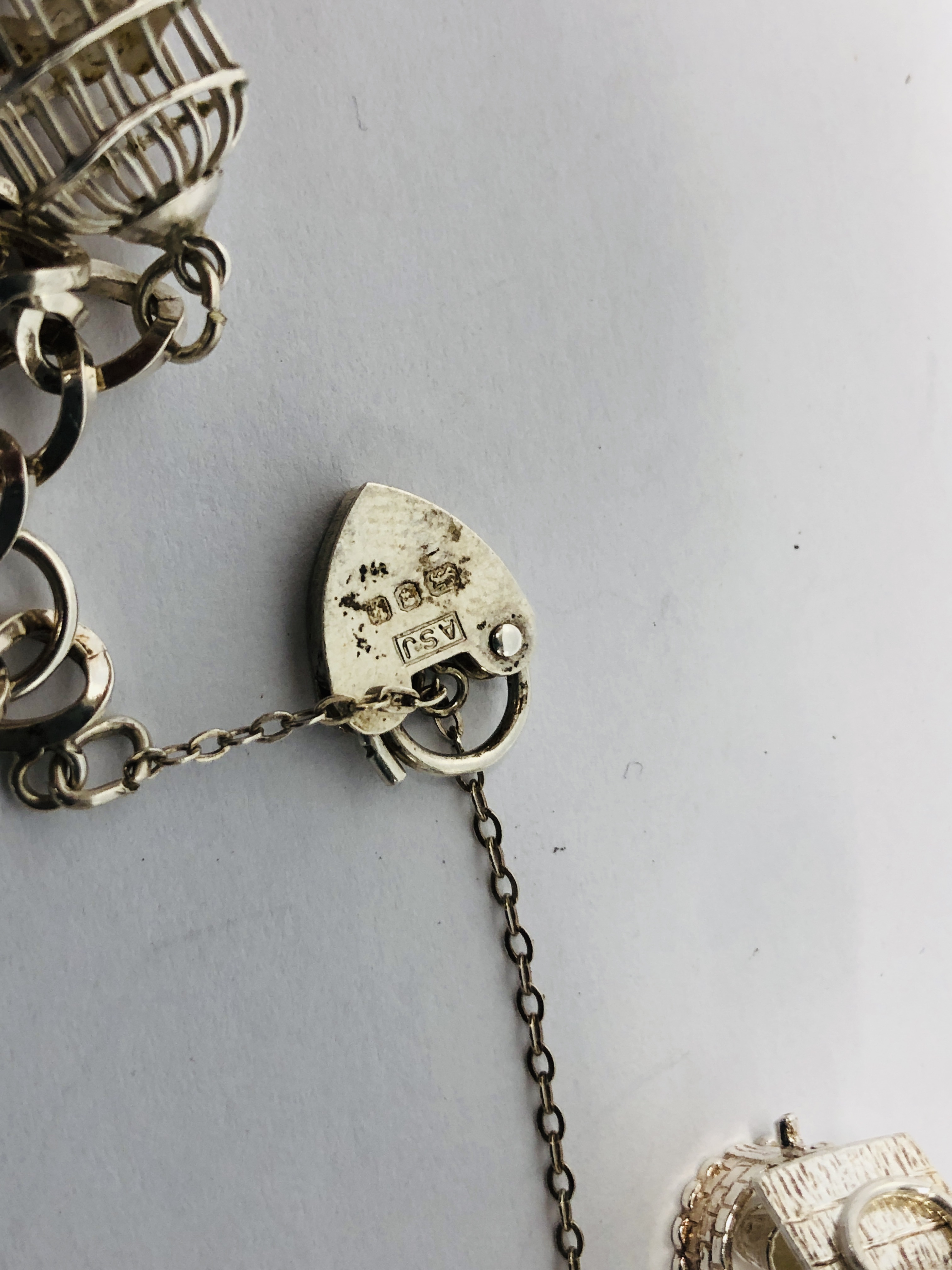 A SILVER CHARM BRACELET WITH FIVE ATTACHED CHARMS TO INCLUDE BIRD CAGE, WISHING WELL, CART ETC. - Image 5 of 8