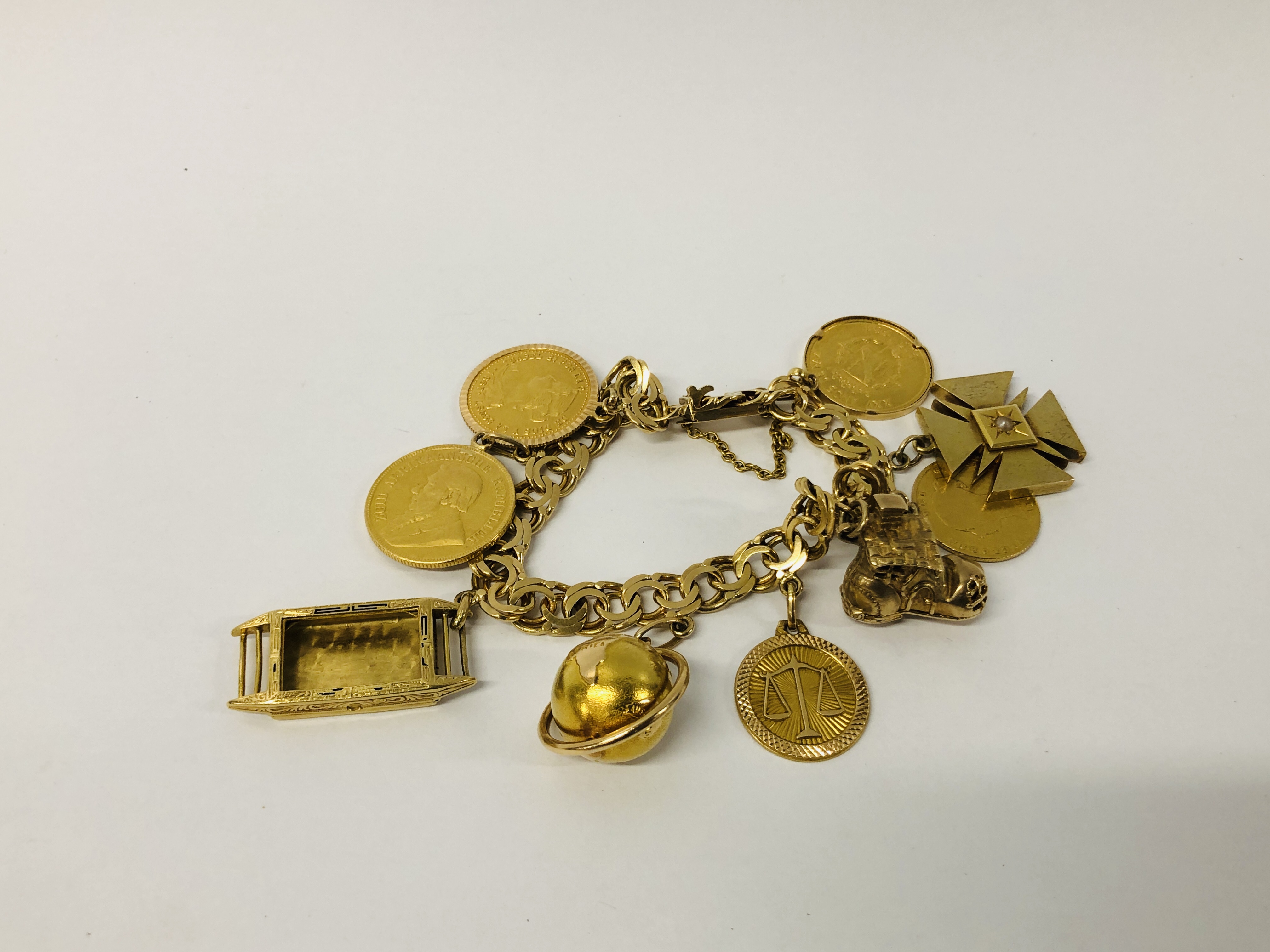 A YELLOW METAL BRACELET (CONTINENTAL MARKS) WITH NINE VARIOUS CHARMS/COINS ATTACHED TO INCLUDE :-
