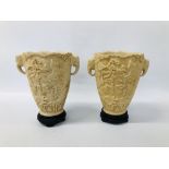 A PAIR OF RESIN DECORATIVE URNS WITH ELEPHANT HEAD DETAIL AND INTERCASE CARVED DESIGN HEIGHT 31CM.