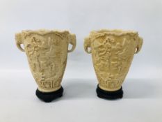 A PAIR OF RESIN DECORATIVE URNS WITH ELEPHANT HEAD DETAIL AND INTERCASE CARVED DESIGN HEIGHT 31CM.