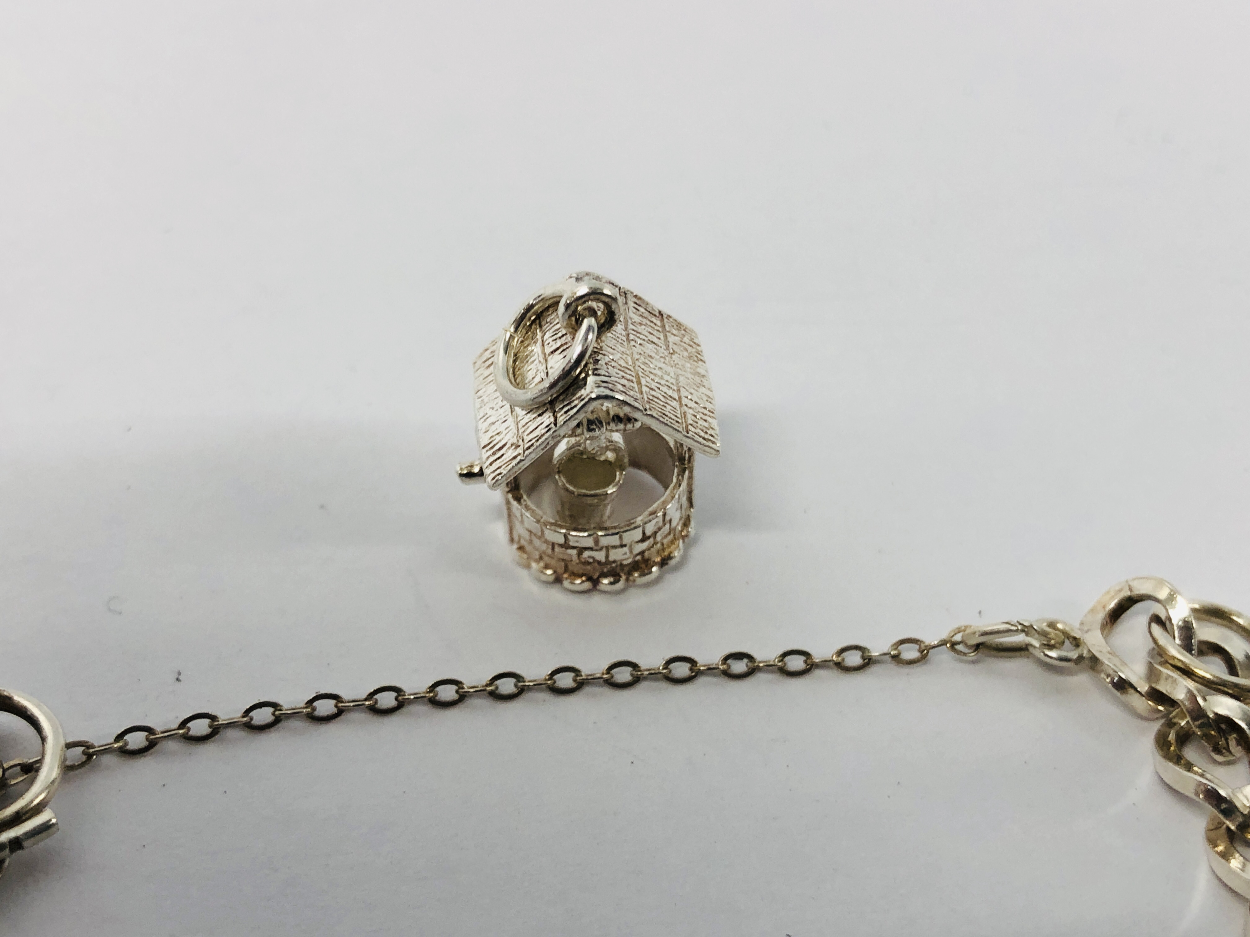 A SILVER CHARM BRACELET WITH FIVE ATTACHED CHARMS TO INCLUDE BIRD CAGE, WISHING WELL, CART ETC. - Image 6 of 8