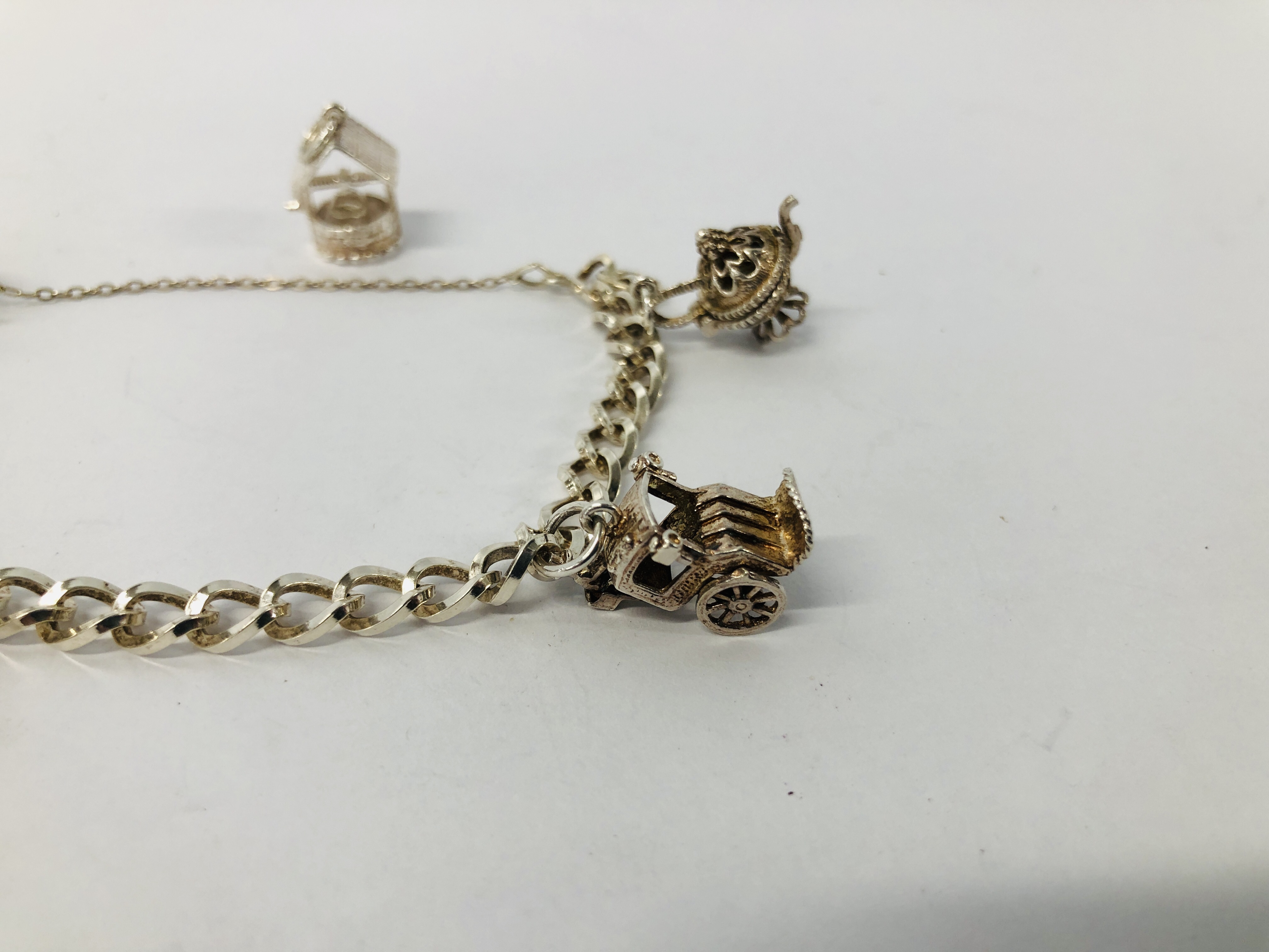 A SILVER CHARM BRACELET WITH FIVE ATTACHED CHARMS TO INCLUDE BIRD CAGE, WISHING WELL, CART ETC. - Image 2 of 8