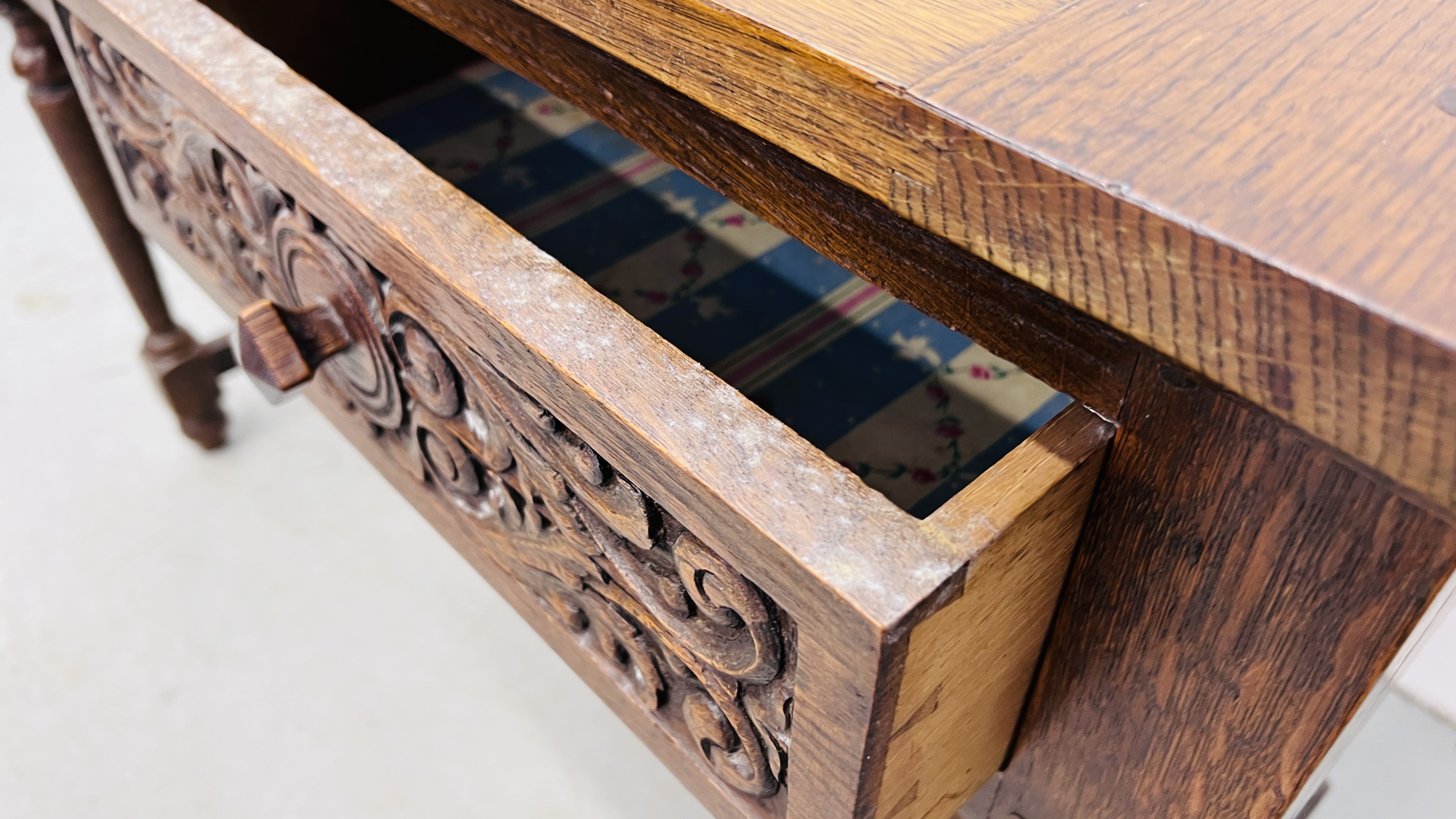 A REPRODUCTION SOLID OAK TWO DRAWER SIDE TABLE WITH CARVED DRAWER FRONTS W 107CM, D 46CM, H 77CM. - Image 9 of 9