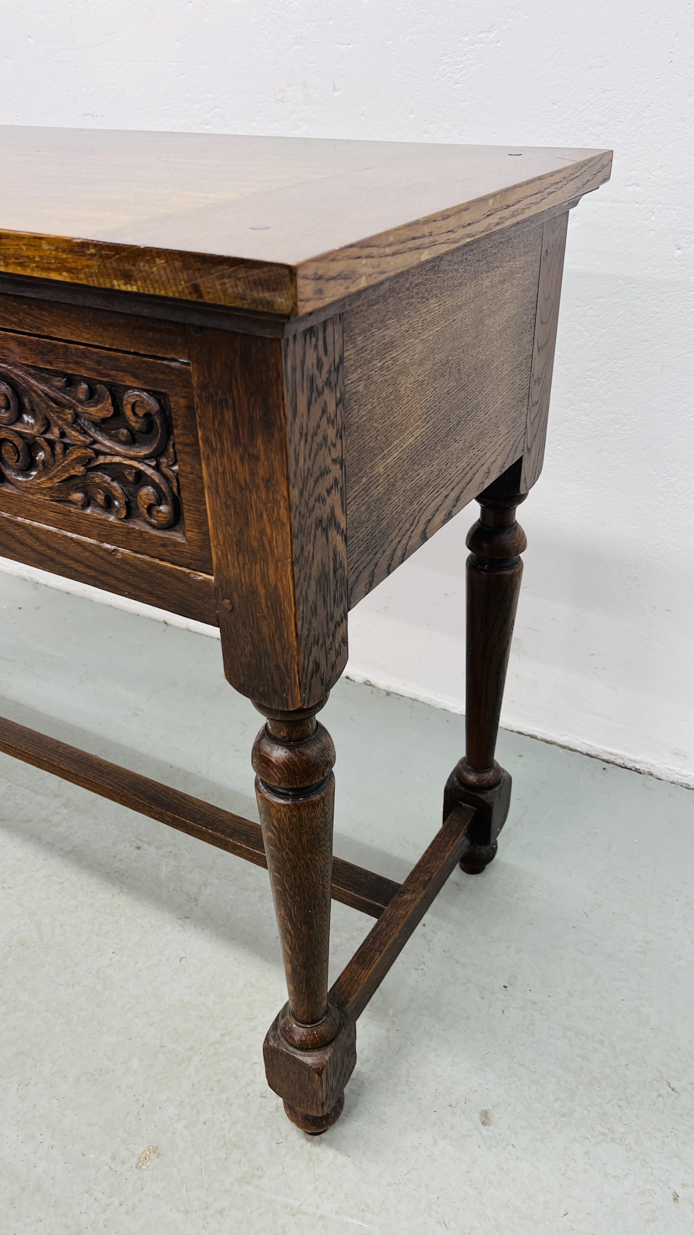 A REPRODUCTION SOLID OAK TWO DRAWER SIDE TABLE WITH CARVED DRAWER FRONTS W 107CM, D 46CM, H 77CM. - Image 6 of 9