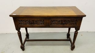 A REPRODUCTION SOLID OAK TWO DRAWER SIDE TABLE WITH CARVED DRAWER FRONTS W 107CM, D 46CM, H 77CM.