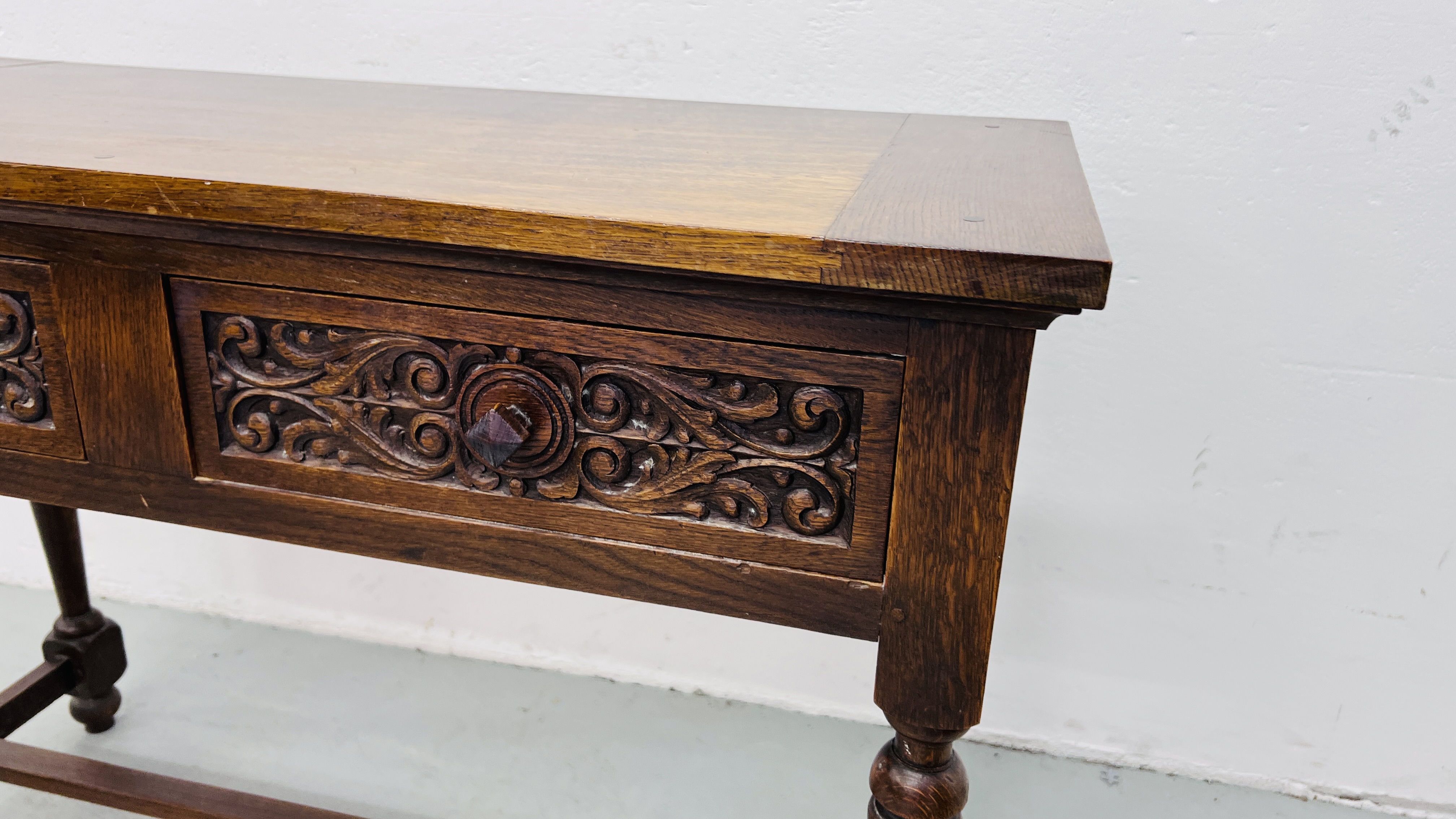 A REPRODUCTION SOLID OAK TWO DRAWER SIDE TABLE WITH CARVED DRAWER FRONTS W 107CM, D 46CM, H 77CM. - Image 5 of 9