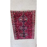 A PERSIAN RUG WITH CONJOINED LOZENGES ON A RED FIELD,