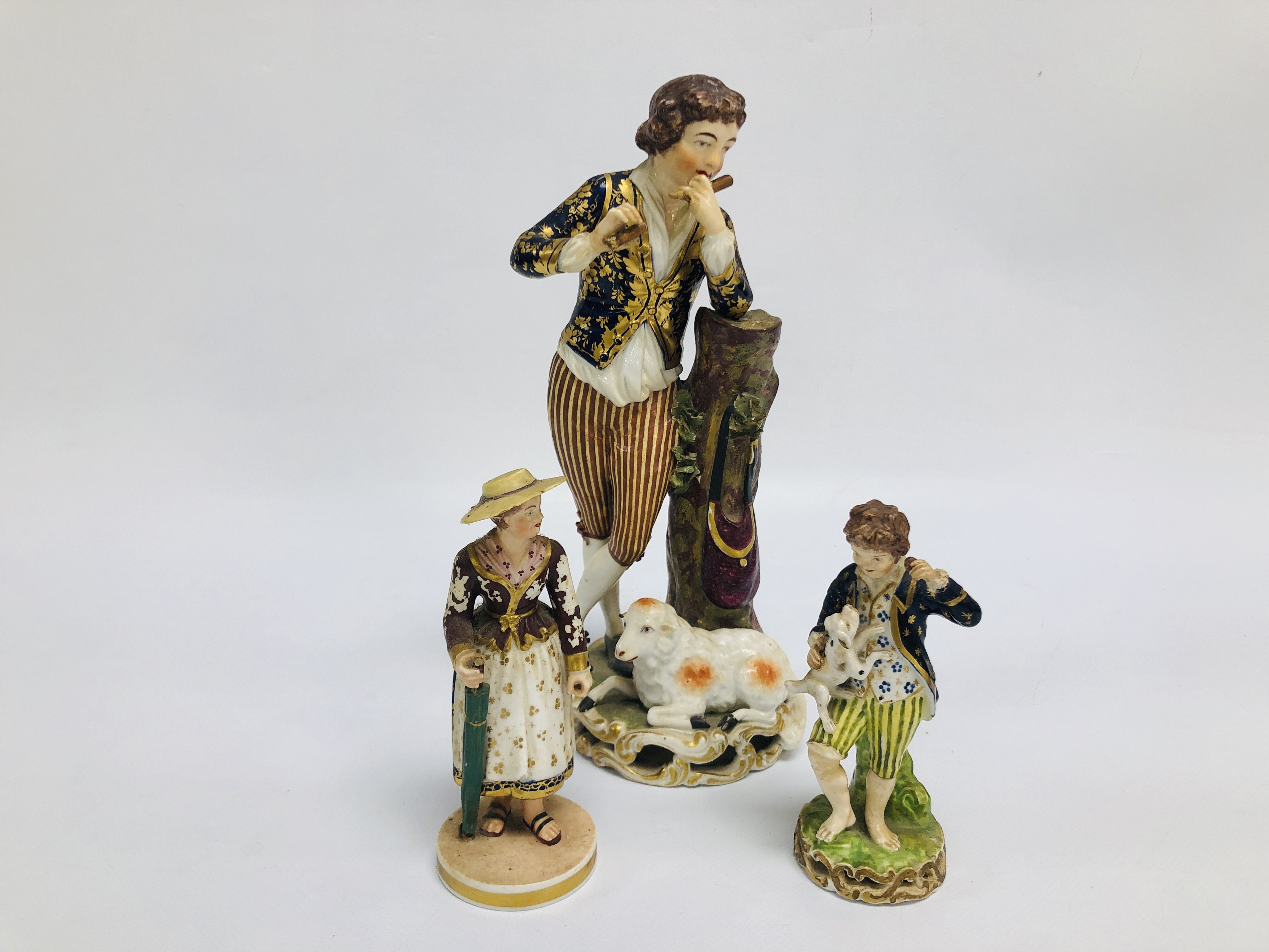 3 X DERBY FIGURES TO INCLUDE A FLAUTIST STANDING BY A RECUMBENT SHEEP (A/F) H 25.