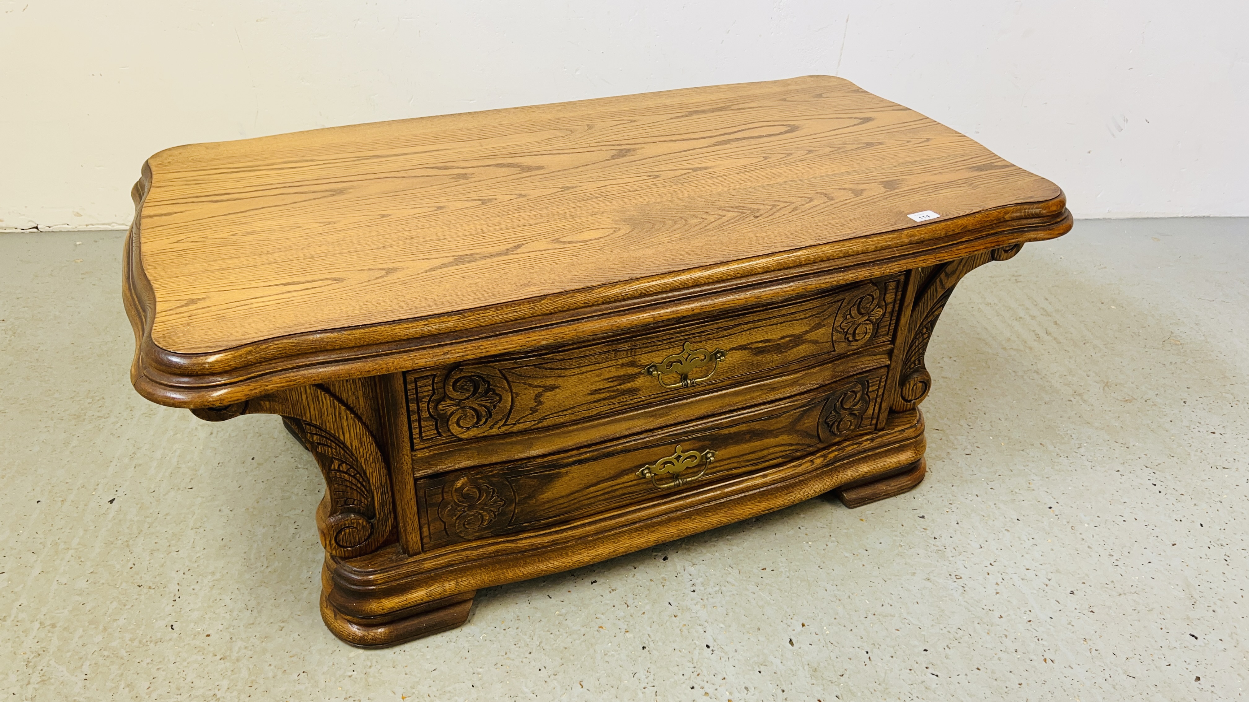 AN OAK TWO DRAWER COFFEE TABLE WITH CARVED DETAIL 120CM X 68CM.