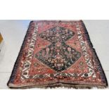 A PERSIAN RUG, THE CENTRAL DOUBLE LOZENGE FILLED WITH LEAF AND VASE MOTIF ON A BRICK RED FIELD,