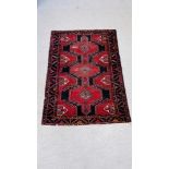 A PERSIAN RUG THE CONJOINED MOTIFS ON A NAVY BLUE FIELD,