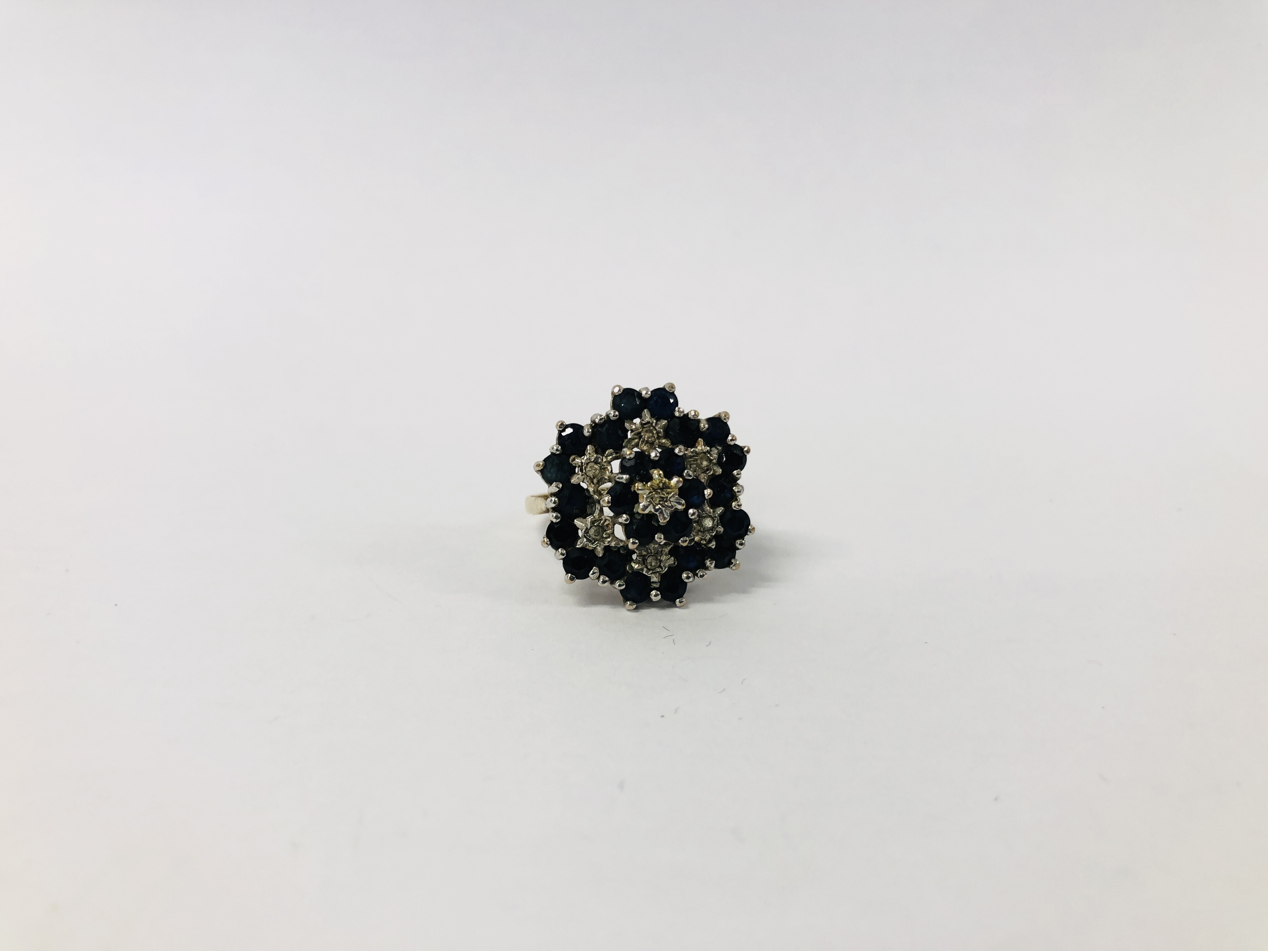 A 9CT. GOLD DIAMOND AND SAPPHIRE RING, SETTING OF FLOWER HEAD DESIGN.